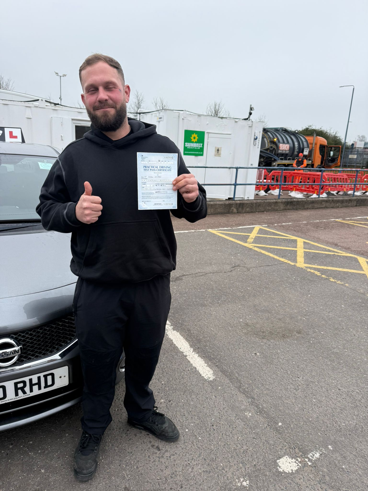 Successful Master Miles student giving thumbs up and holding driving test pass certificate